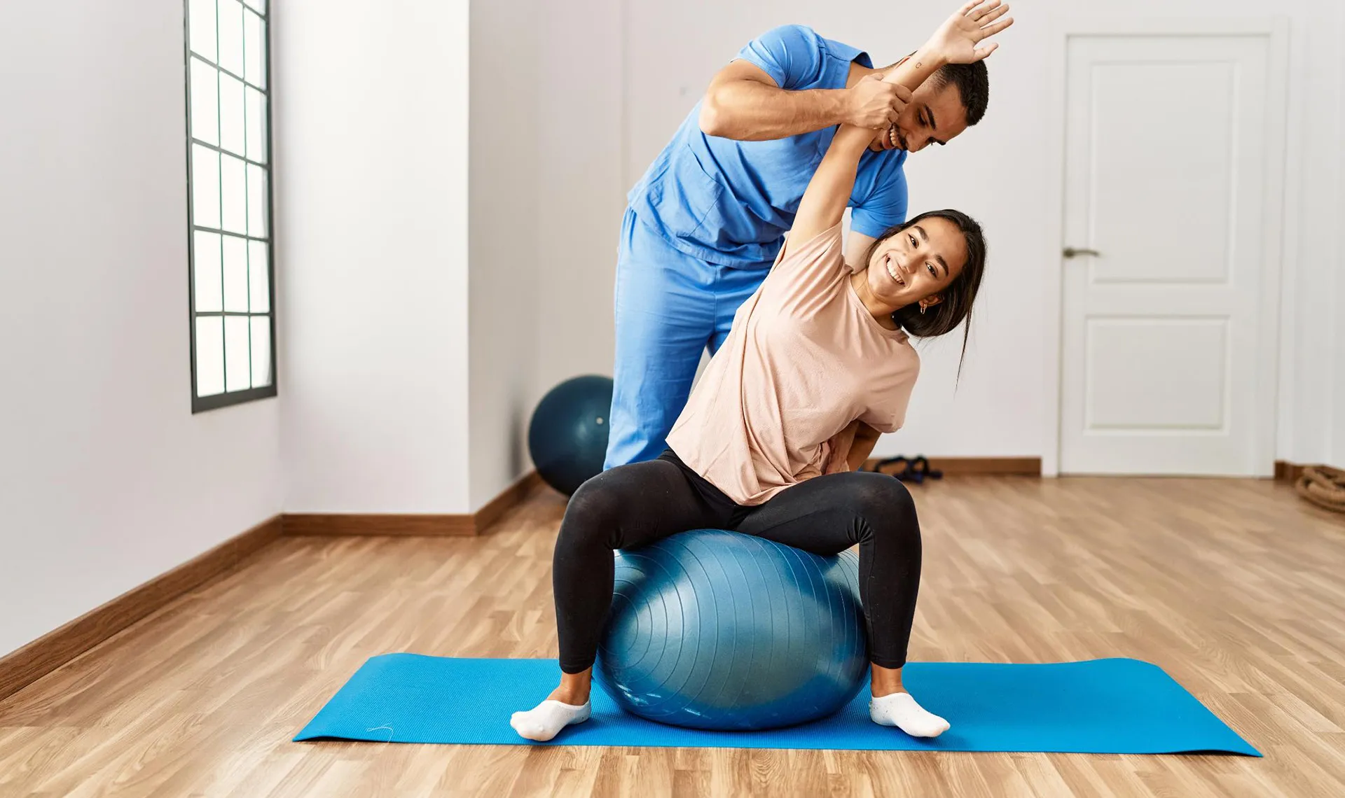 Bewegungstherapie im Reha-Zentrum PV ZAR Wien – Physiotherapeut unterstützt Patientin bei Dehnübung auf Gymnastikball