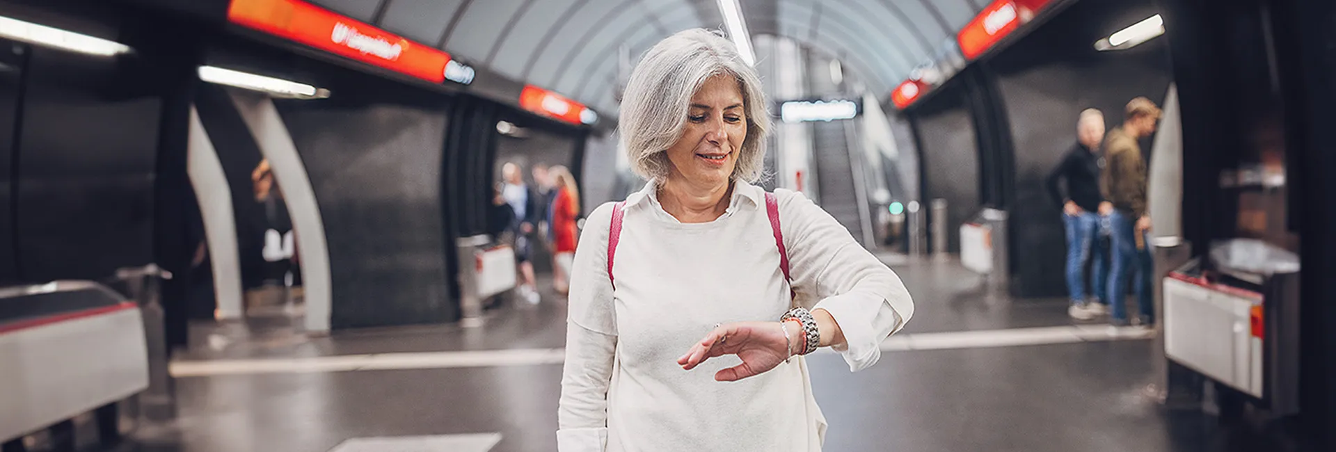 Anreise PV ZAR Wien: Frau steht in U-Bahn-Station und schaut auf die Uhr